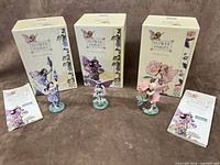 Group shot showing all three figurines, boxes and booklets