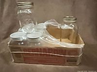Bernardin cardboard tray holding seven small clear glass jars with white lids and one large jar with silver lid