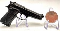 Full left-side view of miniature resin Beretta 92FS with coin for scale