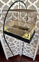 Full view of birdcage on black metal stand