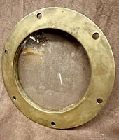 Front view of brass porthole showing glass and bolt holes