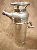 Full view of cylindrical silver-plated pitcher with side handle, lid handle and screw-cap spout