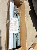 Boxed components showing plastic bases, stacked metal tubes and bag of hardware