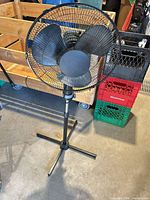 Front view of black pedestal fan showing grille, blades and height