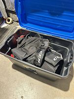 Storage tote containing black CCM hockey pants and other protective gear pieces