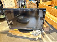 Front view of Dynex 32-inch TV on stand with accessories nearby