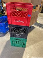 Stacked view of red Sealtest, black Lactalis and green unbranded milk crates