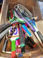 Overhead view of bin containing racquets, paddles and bat