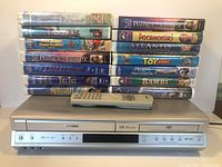 Front view of Toshiba player, remote and two stacks of VHS tapes