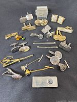 Group shot of all cufflinks, tie bars, money clip and tie tack on black background