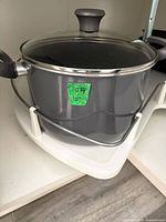 Gray nonstick saucepan with glass lid on shelf