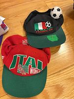Italy World Cup red cap with green brim overlapped by another soccer cap