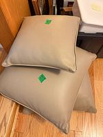 Three beige faux-leather pillows stacked on floor