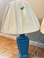 Front view showing blue ceramic base, floral fabric shade and power cord
