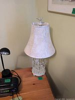Full view of lamp on table showing shade and birdcage base