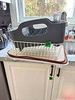 Full view of gray plastic peg rack stacked on white wire basket, plastic tray and beige drying mat