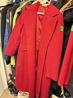 Full view of red Forecaster of Boston overcoat hanging, showing front, lapel, buttons, pockets, lining
