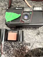 Front view of Fujifilm 35mm point-and-shoot film camera with accompanying 35mm film canister