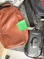 Camera front view beside brown leather case