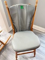 Front view of gray vinyl upholstered wooden dining chair showing seat, backrest and wood frame