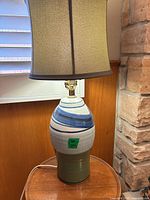 Full lamp showing ceramic base, fabric shade, cord and finial