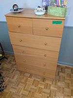 Front view of light wood six-drawer dresser showing drawer configuration and knob pulls
