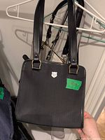 Front view showing bag shape, handles, logo badge
