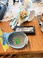 All items together on tabletop: cherub figurine, wicker duck basket, boxed Verdici shoehorn, two ceramic booties