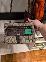 Front view of mini canvas shoulder bag with faux croc buckle detail and printed lettering