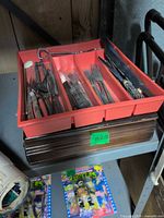 Red plastic cutlery tray on top of wood chest showing assorted utensils and exterior of chest