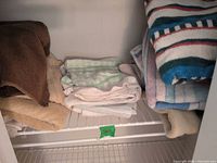 Stacked assorted cotton bath and hand towels on wire shelf