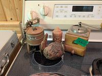 Group shot showing all four items on stovetop: coffee grinder, Maytag washer model, Buddha head, coconut fish carving