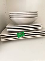 Stack of dinnerware showing square dinner plates, square salad plates, round plates and round serving bowl