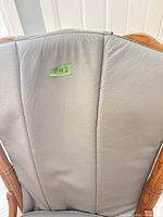 Backrest of dining chair showing gray leather upholstery and oak frame