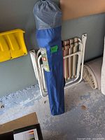 Blue Ozark Trail carry bag holding folding chair beside white striped folding beach chair