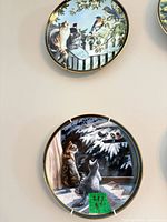 Two cat-themed porcelain plates on wall with hangers