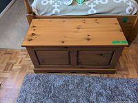 Front and top view of pine blanket chest showing honey finish and paneled front