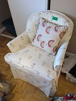 Skirted upholstered armchair with floral print and decorative pillow