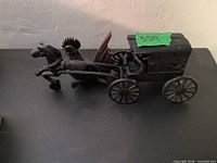 Full view of cast iron horse-drawn carriage with attached horse; carved rooster visible behind