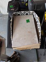 Box of white ceramic tiles showing damaged packaging and top tile