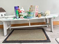 Full view of white distressed wooden bench with items placed on top showing size and design