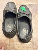 Top view of both shoes showing black leather, moc toe stitching, bow detail, Dexter Comfort insoles