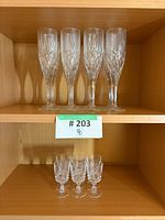 Six pressed glass champagne flutes and four cordial glasses on shelf