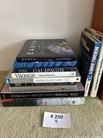 Full stack of nine large hardcover books with several titles visible