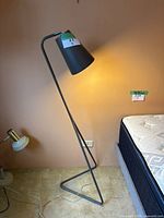 Lamp angled beside bed showing shade lit and cord