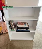 Front view of white bookshelf with two shelves installed and books for scale