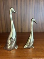 Front view of both brass duck figurines on shelf