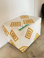 Front and side view of cube ottoman showing upholstery and pattern