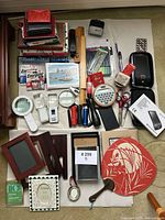 Entire lot laid out showing markers, notebooks, magnifiers, frames, flashlights, batteries and accessories