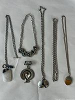 Group shot of all five necklaces laid flat showing pendants and chains